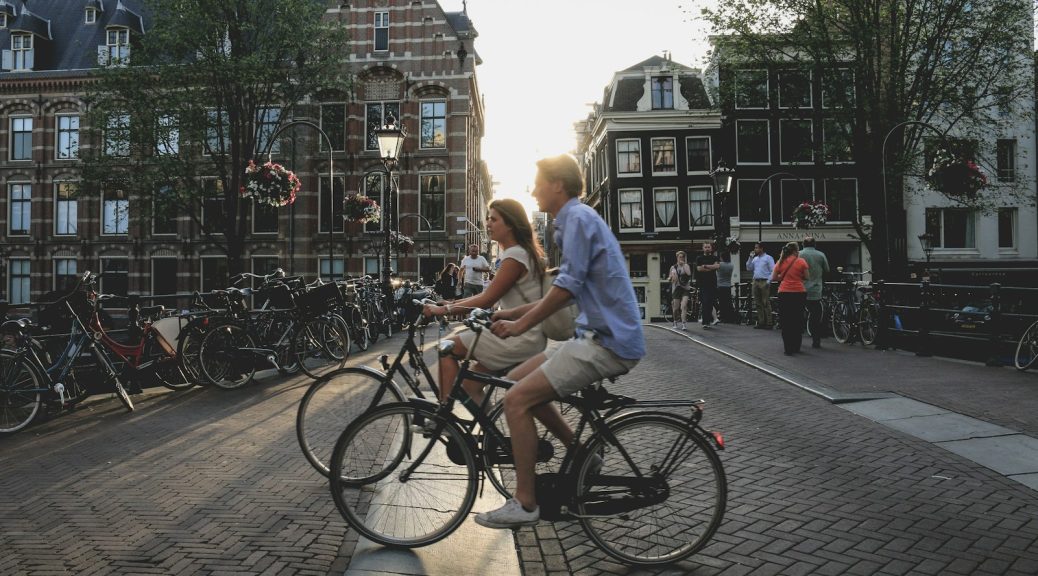 man and woman biking along city at daytime